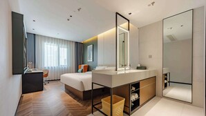 A modern hotel room with a large bed, a vanity with a mirror, a small desk, and a wicker basket. - Tingxi Hotel Science Avenue Subway  (Hefei)