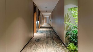A long, narrow hallway with a patterned carpet, wooden doors, and a plant on the right. - Tingxi Hotel Science Avenue Subway  (Hefei)