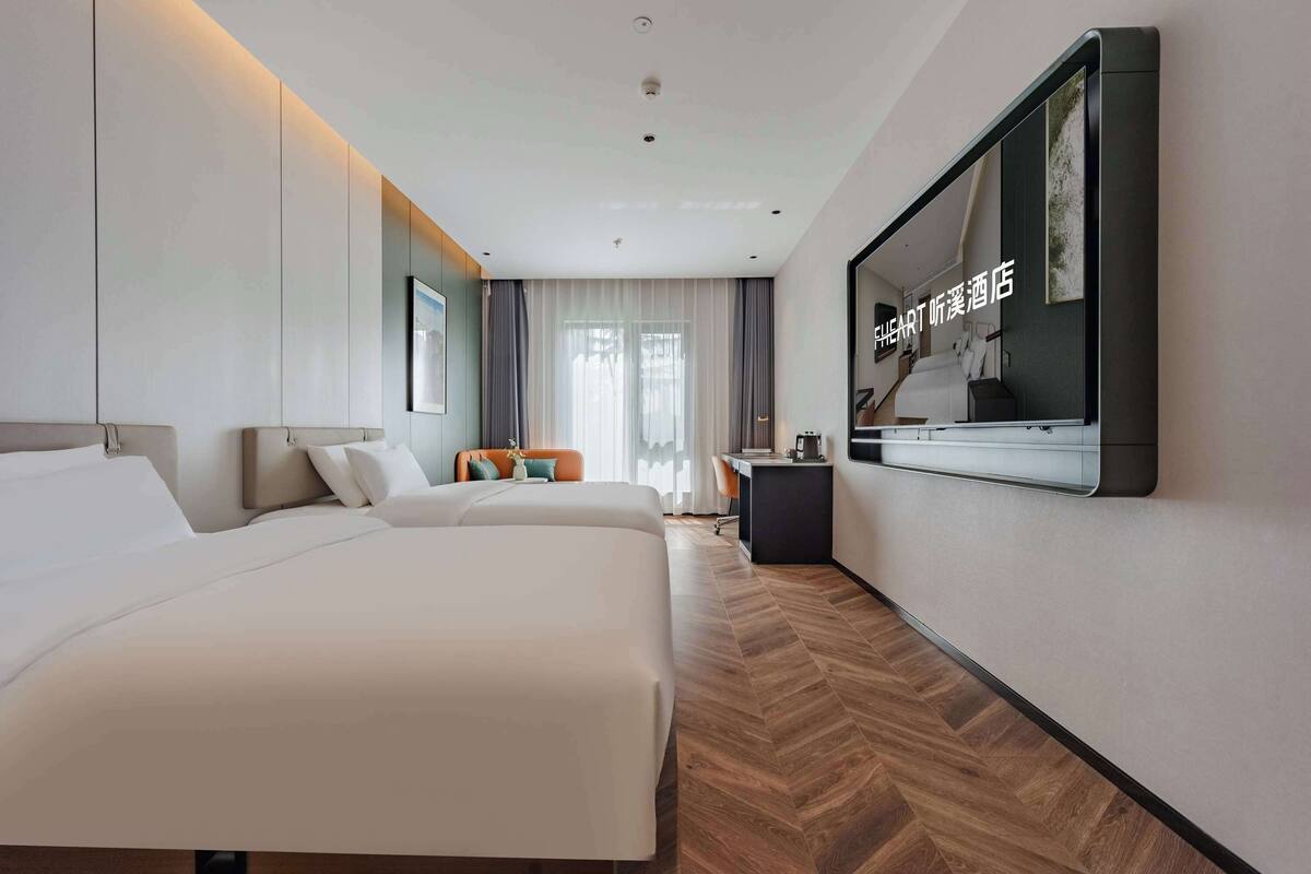 A hotel room with two beds, a desk, and a large mirror.