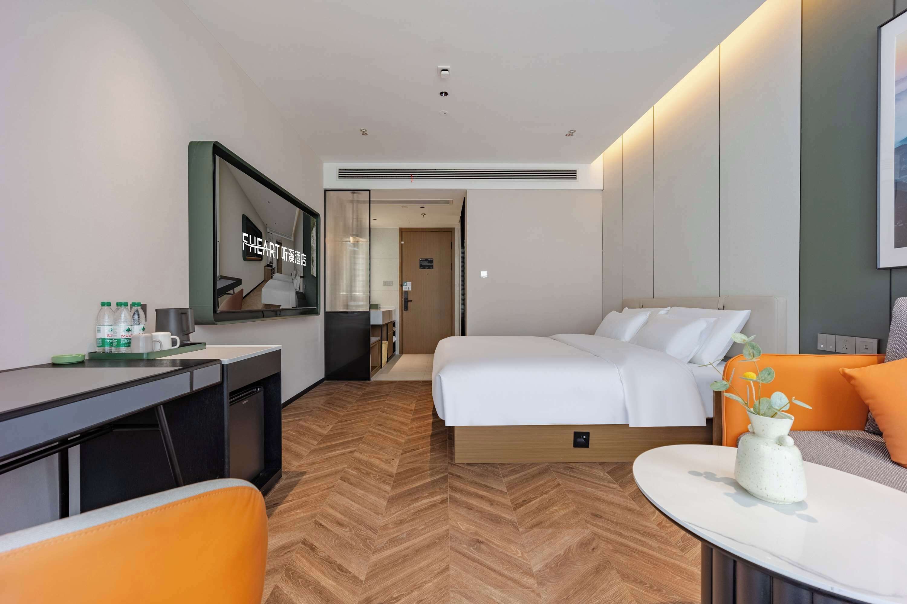 Habitació d'hotel moderna amb llit, escriptori i cadira, taula petita amb un ram i un mirall a la paret.