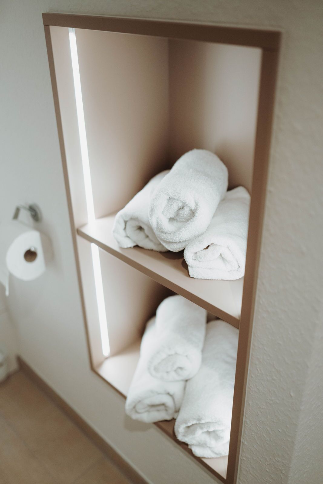 A shelf with three neatly folded white towels.