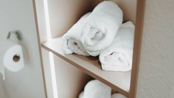 A shelf with three neatly folded white towels.