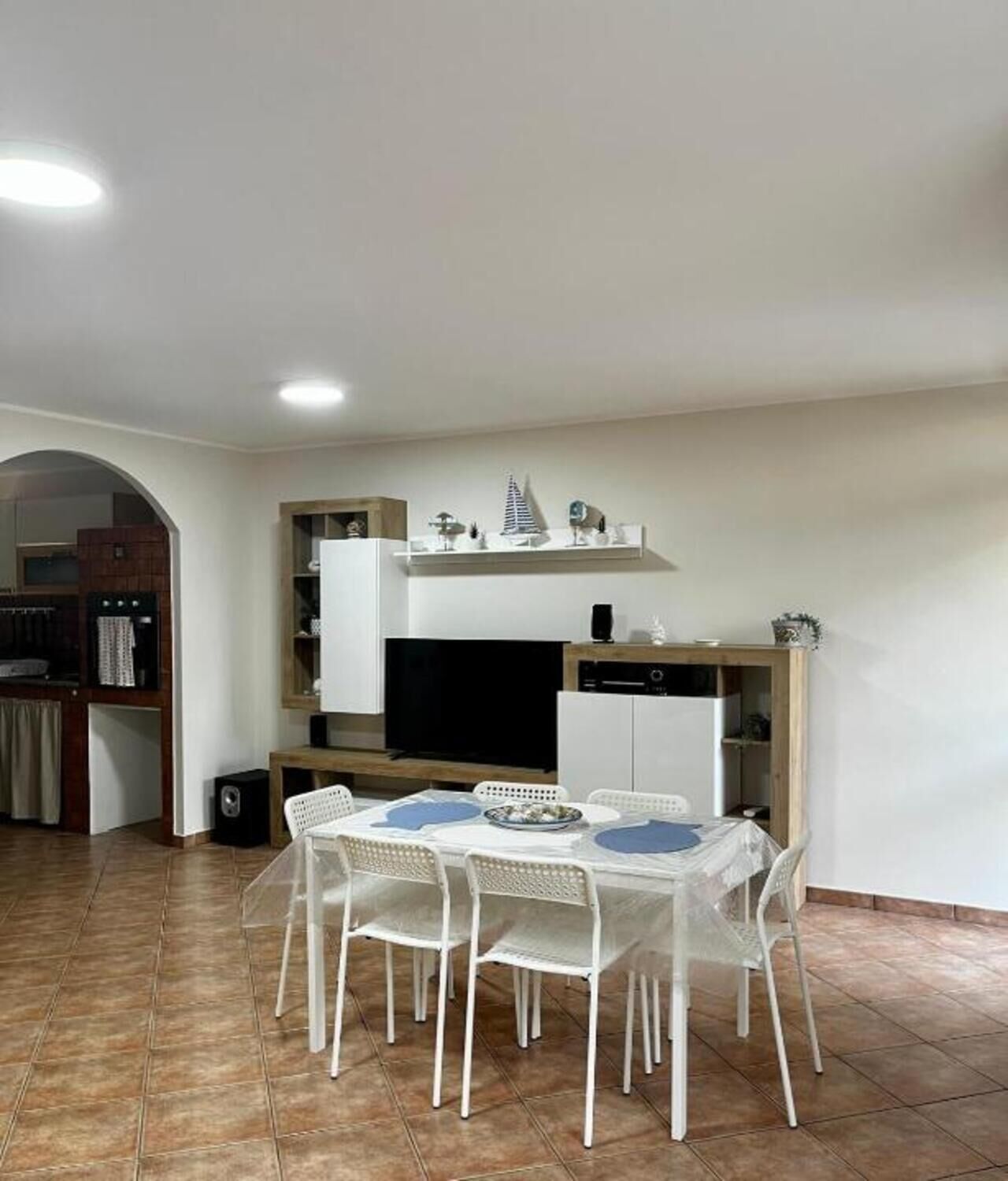 A compact kitchen with a dining table and chairs, a built-in oven, and a small refrigerator.