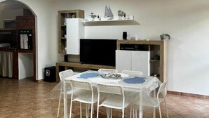 A compact kitchen with a dining table and chairs, a built-in oven, and a small refrigerator. - Reysol Home (Costa Saracena - Castelluccio)