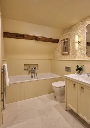 Ein Badezimmer mit Badewanne, Toilette, Waschtisch und Spiegel.