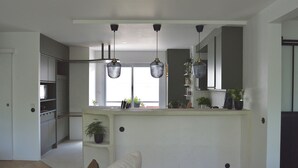 Een moderne keuken met hanglampen, een inbouwkookeiland en uitzicht op de omgeving.