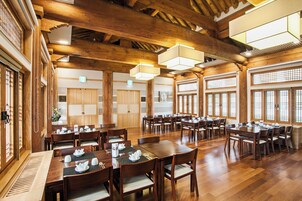 Un amplio comedor con mesas y sillas de madera, ventanas grandes y vigas de madera tradicionales en el techo.