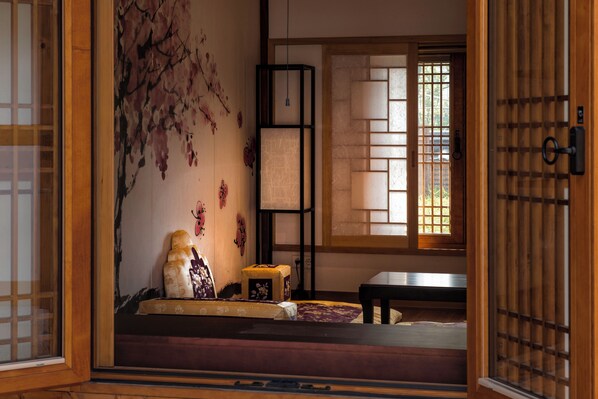 Una stanza tradizionale giapponese con pavimento in tatami, paravento shoji e un murale con fiori di ciliegio.