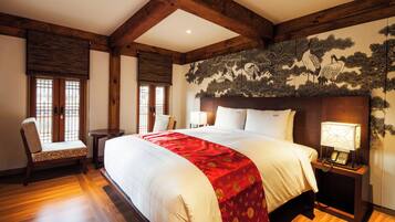 A hotel room with a large bed, wooden beams, a traditional Japanese-style wall hanging, and a small bedside table with a lamp.
