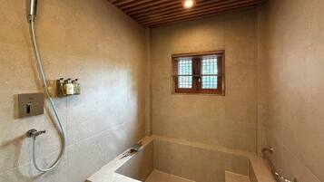 Une salle de bain avec une baignoire, une douche et une fenêtre avec des stores.