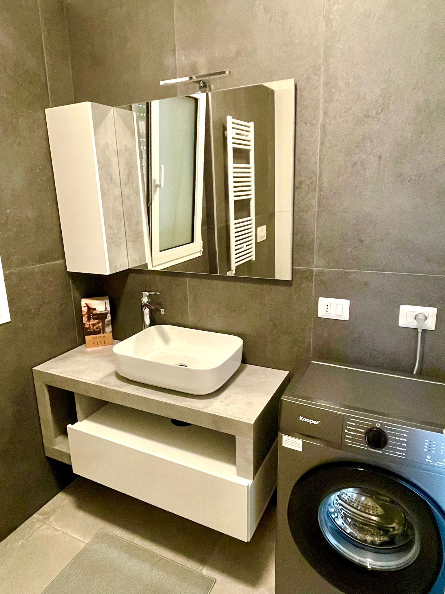 Une salle de bain moderne avec un lavabo intégré, un miroir, un porte-serviettes et un lave-linge.