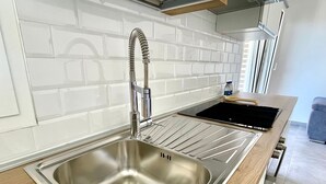 A modern kitchen with a stainless steel sink, a wooden countertop, and a black induction cooktop. - NEW! 2 Bedrooms, 2 Bathrooms, Free Car Box 100m from the sea (Alba Adriatica)