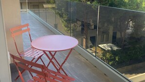 A balcony with a red metal table and chairs, a glass railing, and a view of trees and buildings. - NEW! 2 Bedrooms, 2 Bathrooms, Free Car Box 100m from the sea (Alba Adriatica)