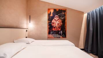 A hotel room with a bed, white bedding, a wall-mounted artwork, and a window with curtains.