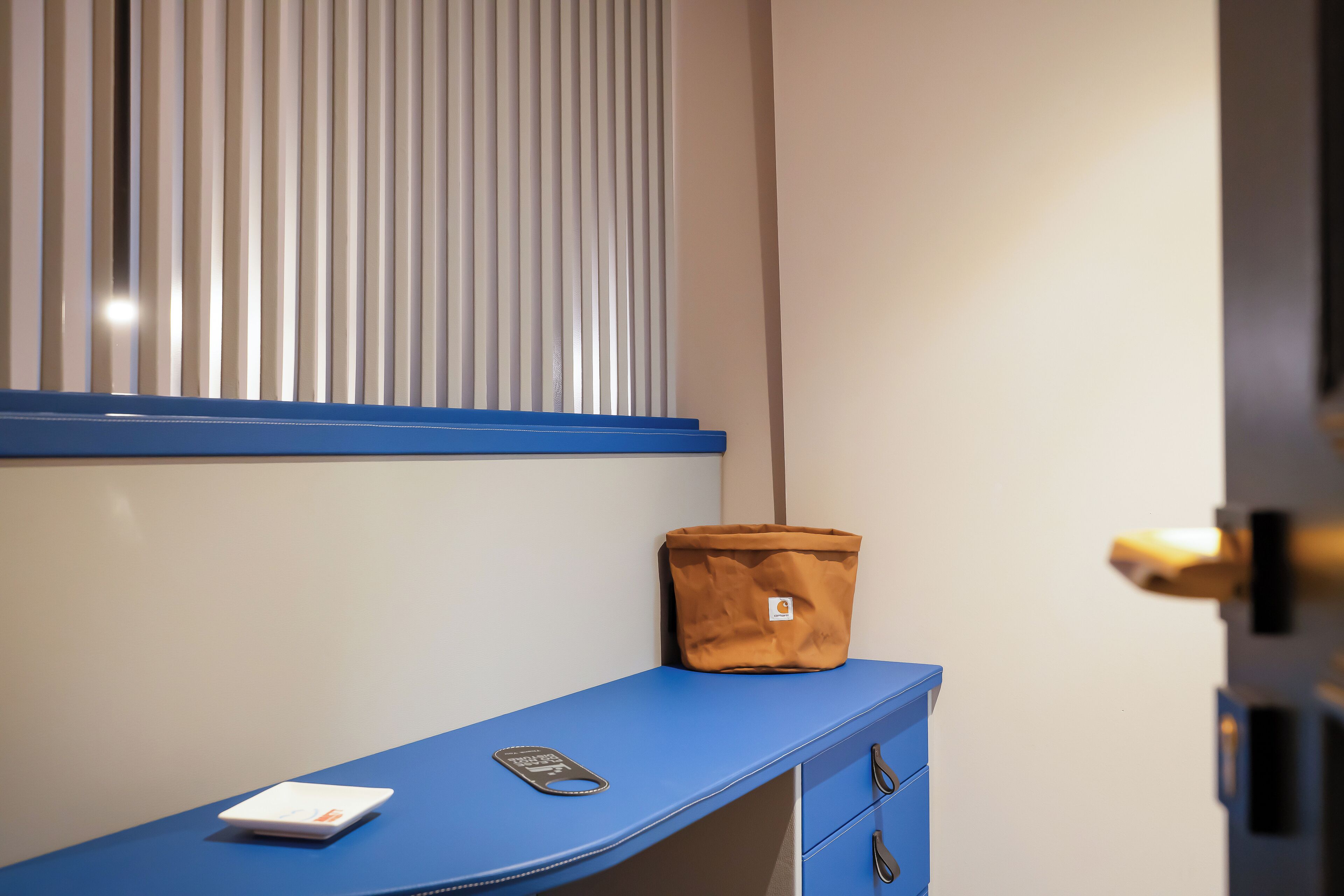 A blue desk with a scale, a brown bag, and a door handle.