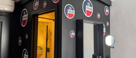 Une pièce avec une porte, un miroir et plusieurs logos « Fusalp » sur les murs.
