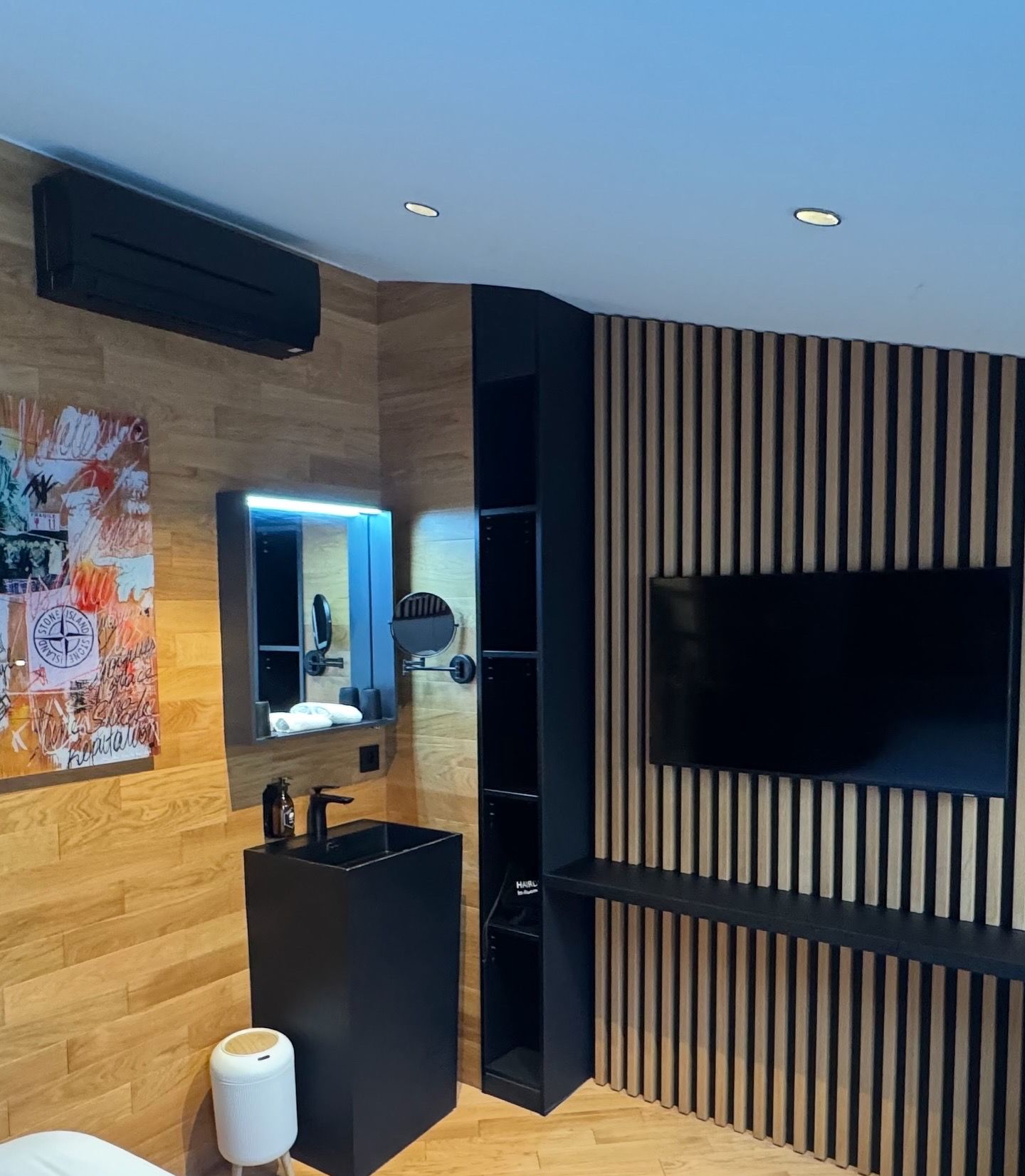 A modern bathroom with a wooden vanity, a mirror, and a black sink.