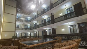 A multi-level hotel lobby with wicker furniture and a central glass-top table. - Silk Road Terrace  (Bukhara)