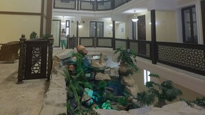 A multi-level hotel interior with a central courtyard featuring a water feature and stone walls. - Silk Road Terrace  (Bukhara)
