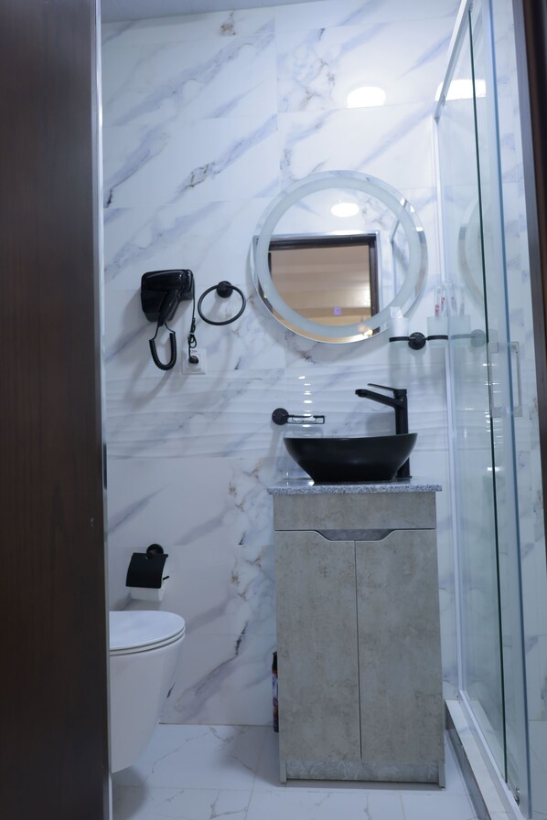 A bathroom with a marble wall, a black sink, a mirror, and a toilet. - Silk Road Terrace  (Bukhara)
