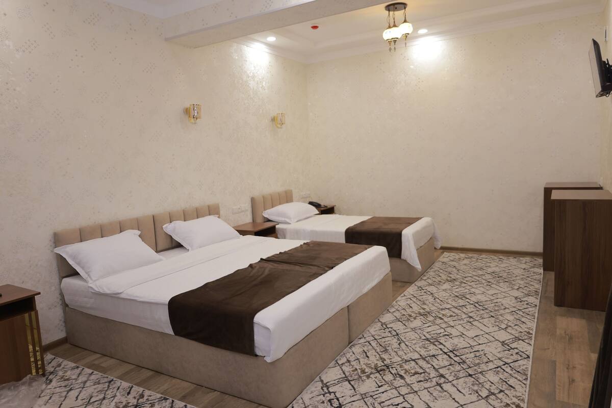 Une chambre d’hôtel avec deux lits, une table de chevet en bois, un tapis à motifs et un bureau en bois.