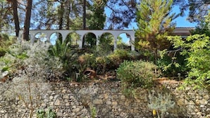A garden with a stone wall, a pergola, and various plants. - Charming Villa in Moniatis, Cyprus - Private Pool & Garden (Saittas)