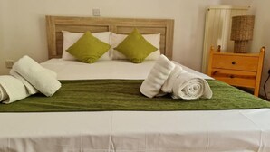 A neatly made bed with a green bedspread, two pillows, and rolled towels on the side. - Charming Villa in Moniatis, Cyprus - Private Pool & Garden (Saittas)