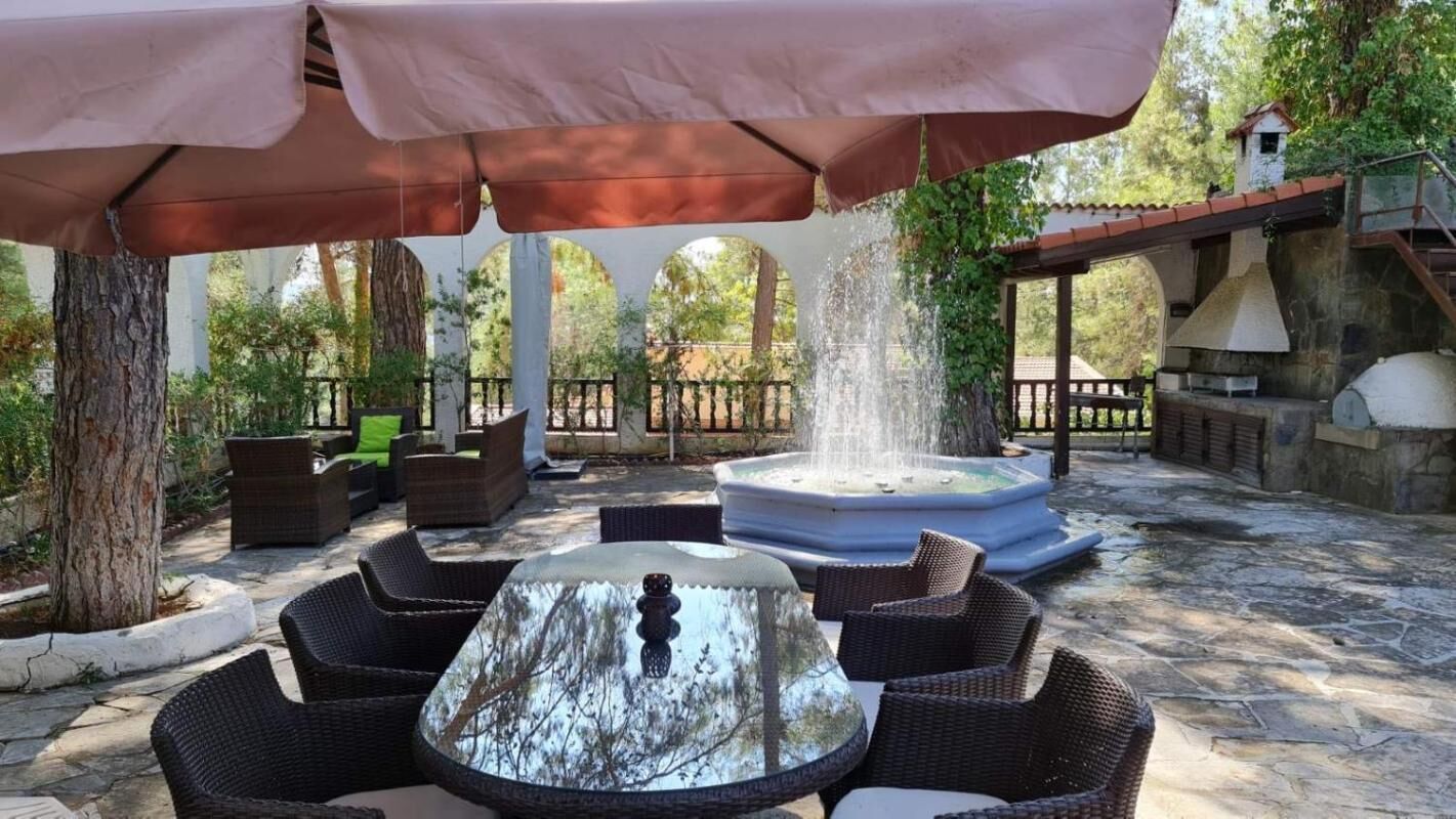 Un patio al aire libre con mobiliario de mimbre, una mesa central y una fuente de agua.