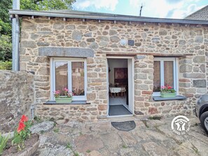Una casa de piedra con dos ventanas, una puerta y un pequeño porche.