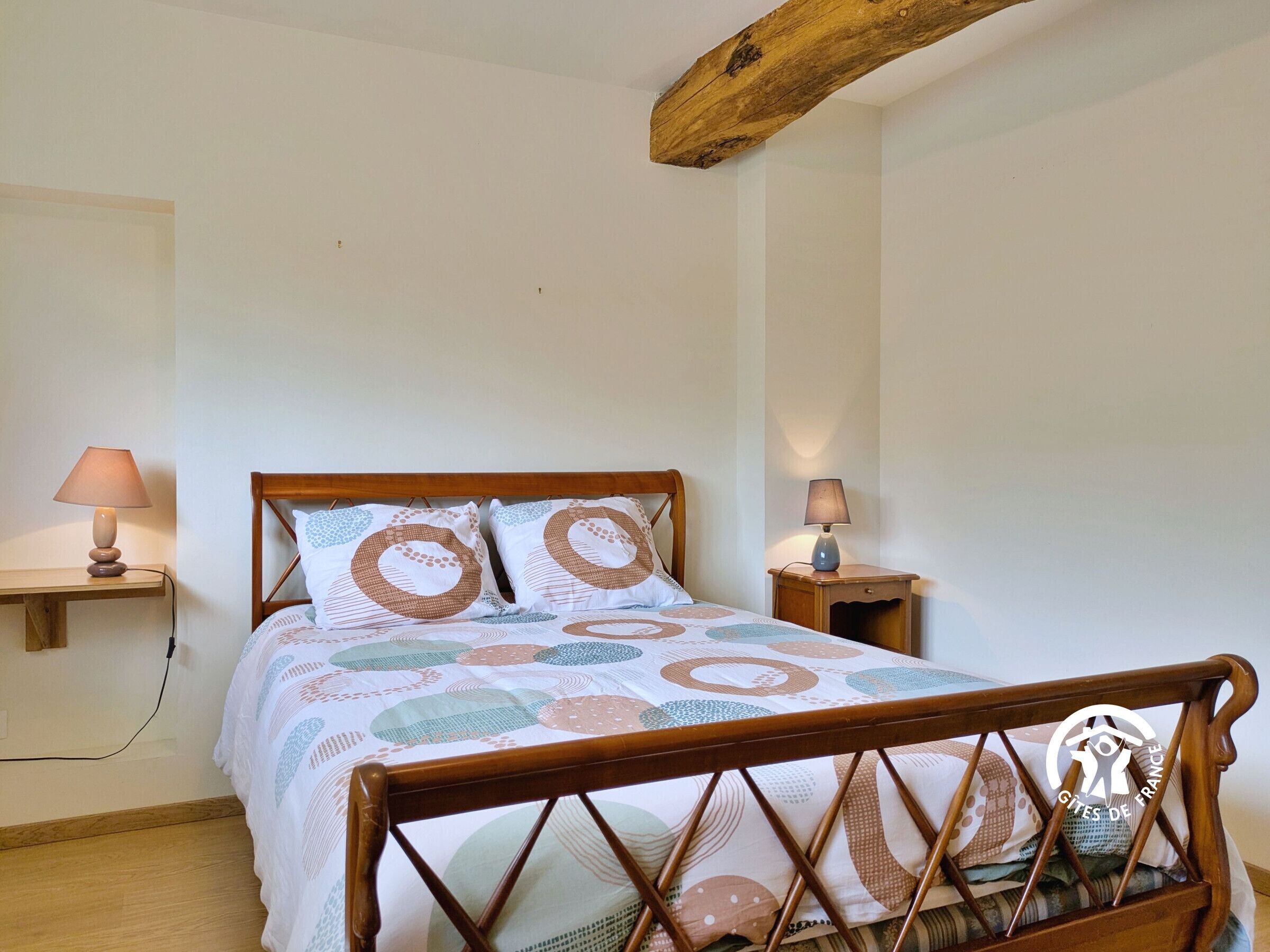 Une chambre à coucher avec un lit en bois, deux lampes de chevet et une couvre-lit à motifs.