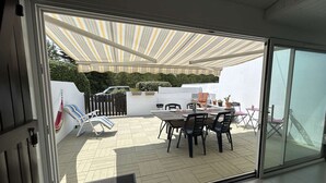 Eine Terrasse mit Tisch, Stühlen, einer Hängematte und einem Grill.