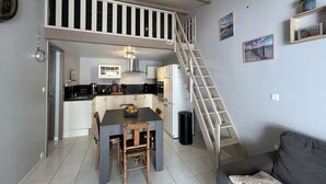 Ein kompakter Wohnraum mit einer Küche, einem Essbereich und einer Treppe zu einer oberen Ebene.