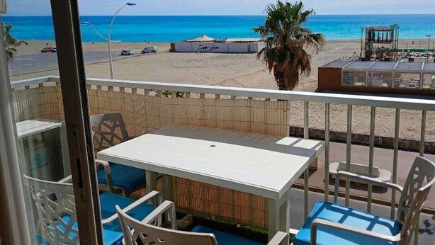 A balcony with a view of the beach, a table, chairs, and a palm tree. - Beautiful 2-Room with WIFI, AC - Pets Allowed (Canet-en-Roussillon)