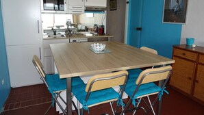 A compact kitchen with white cabinets, a wooden table, and teal chairs. - Beautiful 2-Room with WIFI, AC - Pets Allowed (Canet-en-Roussillon)