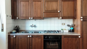 Eine Küche mit Holzausstattung, einem Edelstahlspülbecken, einem Gasherd und einem Geschirrspüler.