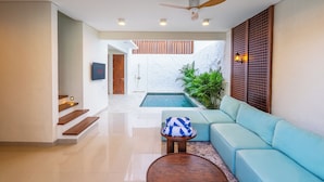 Ein modernes Interieur mit Schwimmbad, einem hellblauen Sofa und einem Deckenventilator.