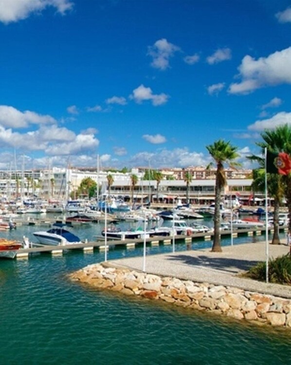A marina with boats docked, a stone jetty, and a clear blue sky. - Lagos Marina- Excellent Location- Close To Beach (Lagos)
