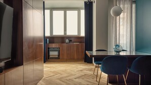 A modern kitchen with wooden cabinets, a built-in oven, and a dining area with a table and chairs. - Modern apt near the Centre (Milan)