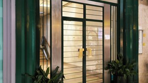 A building entrance with a green door, a staircase leading inside, and potted plants on the ground. - Modern apt near the Centre (Milan)