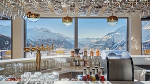 A bar area with a mountain view, a bar tap, and various bottles and glasses.