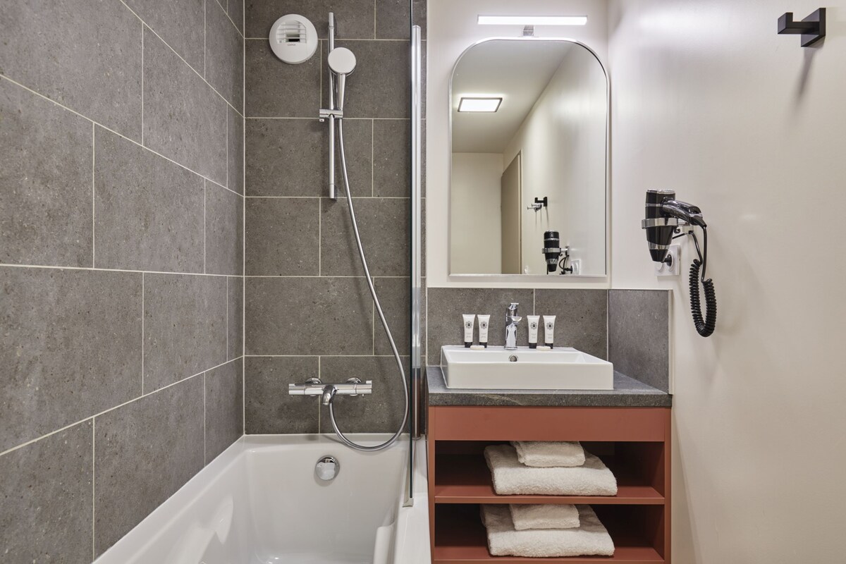 Un baño moderno con bañera, ducha, lavabo y espejo.