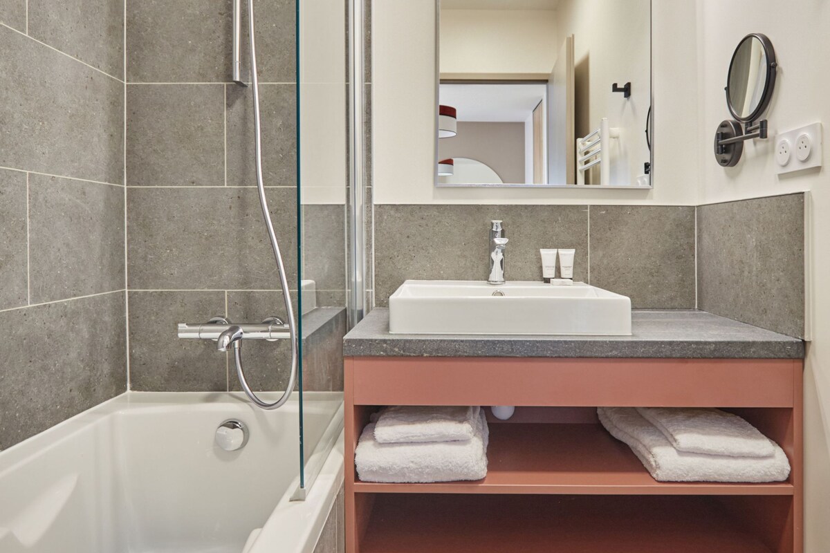 Un baño moderno con bañera, lavamanos y espejo.