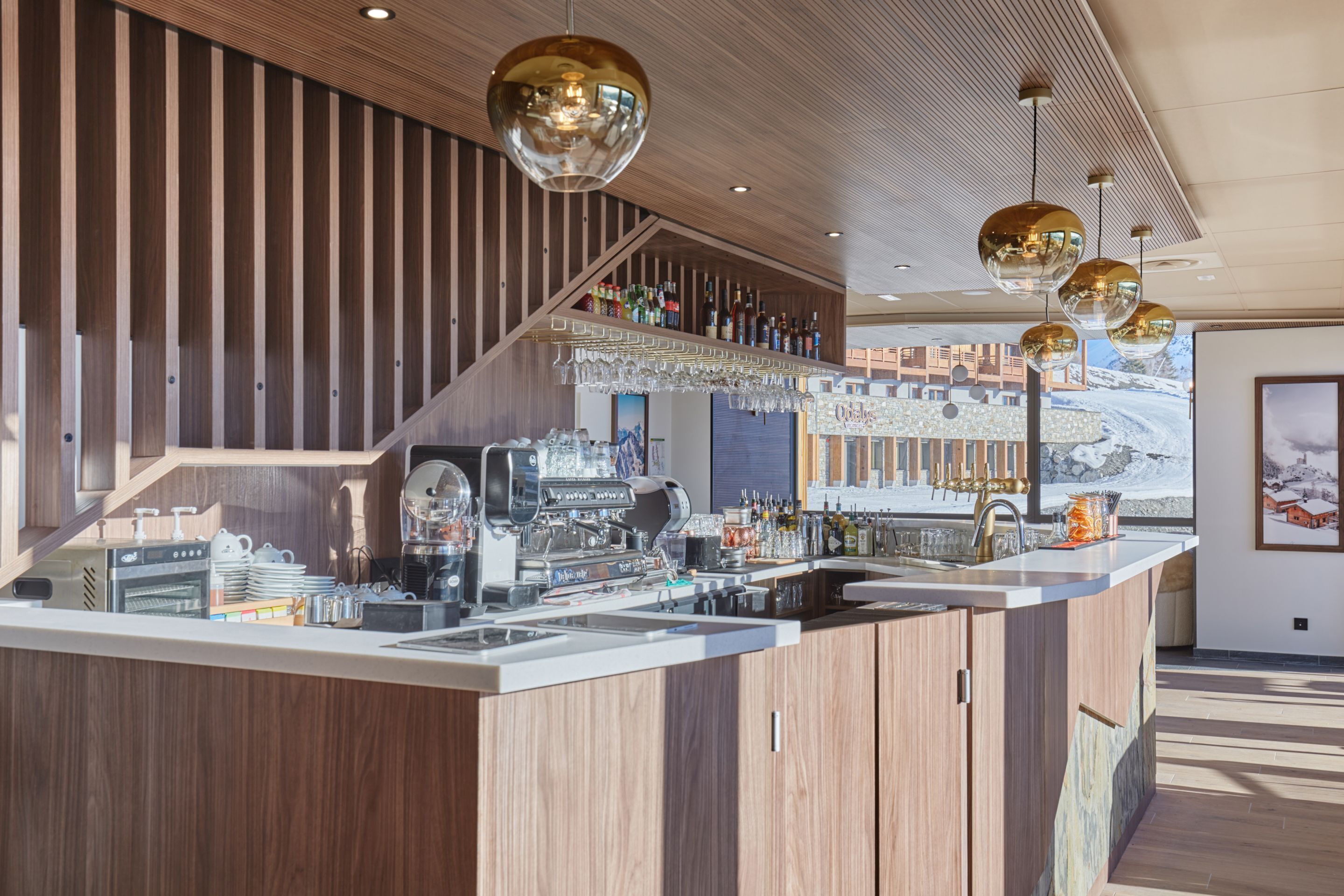Un'area bar moderna con un bancone in legno, una macchina per espresso e una selezione di bottiglie.