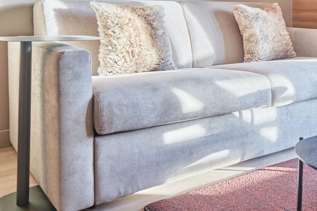 A modern living room with a sofa, two wall-mounted lights, and a large abstract artwork.