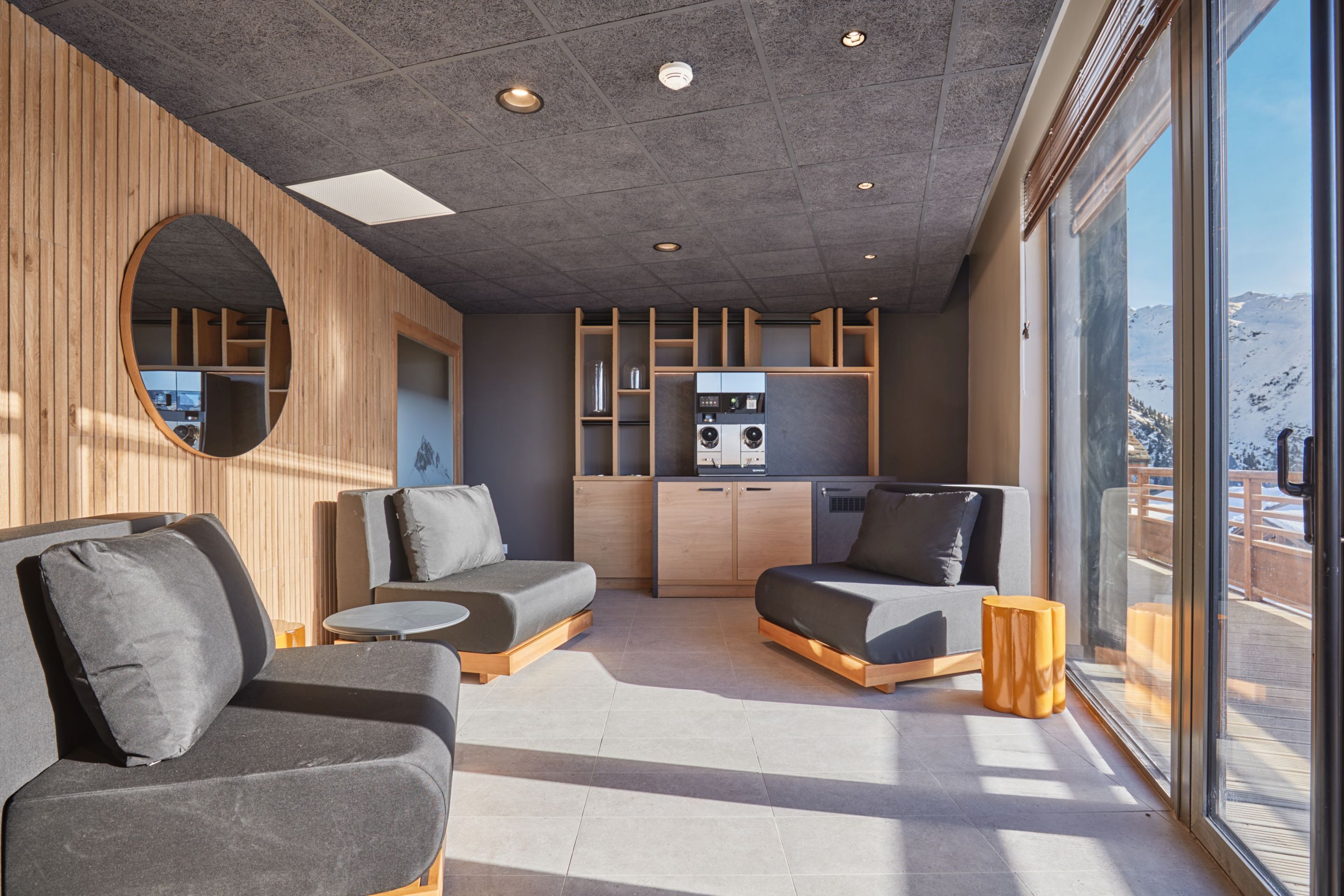 A modern interior with a sofa, a small table, and a kitchen area with cabinets and appliances.