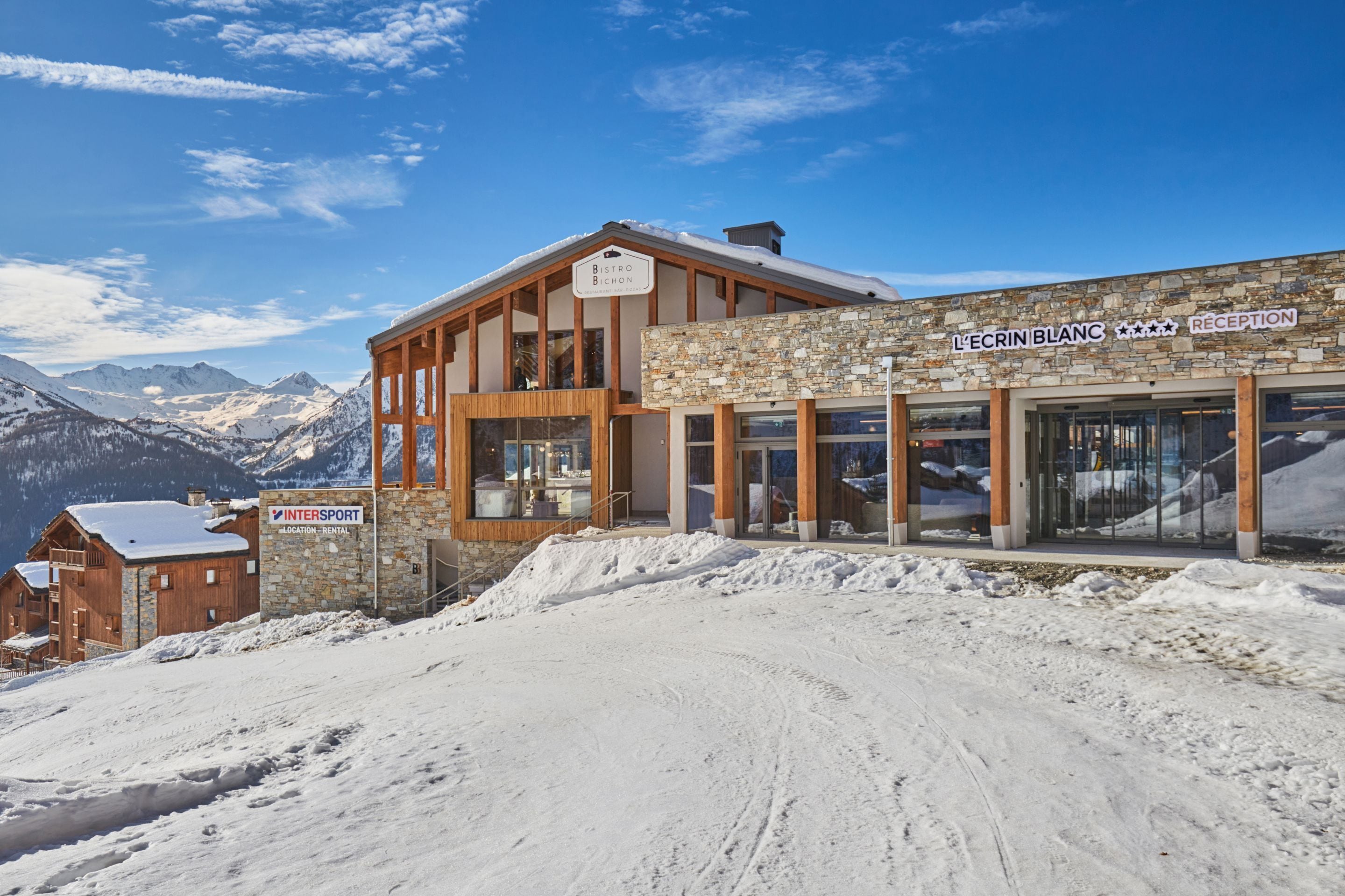 A mountain lodge with a reception area and a restaurant named 'L'Ecrin Blanc'.