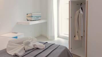 Un dormitorio moderno con cama, mesita de noche, maleta y armario.
