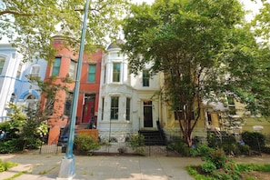 A row of multi-story townhouses with a central white building featuring a rounded corner and a dome.