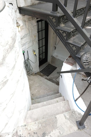 A staircase leading to a door with a metal railing and a small step at the bottom.