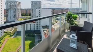 A balcony with a view of a cityscape, including high-rise buildings and a green park area. - Spektrum 2 by Grand Apartments (Gdansk)